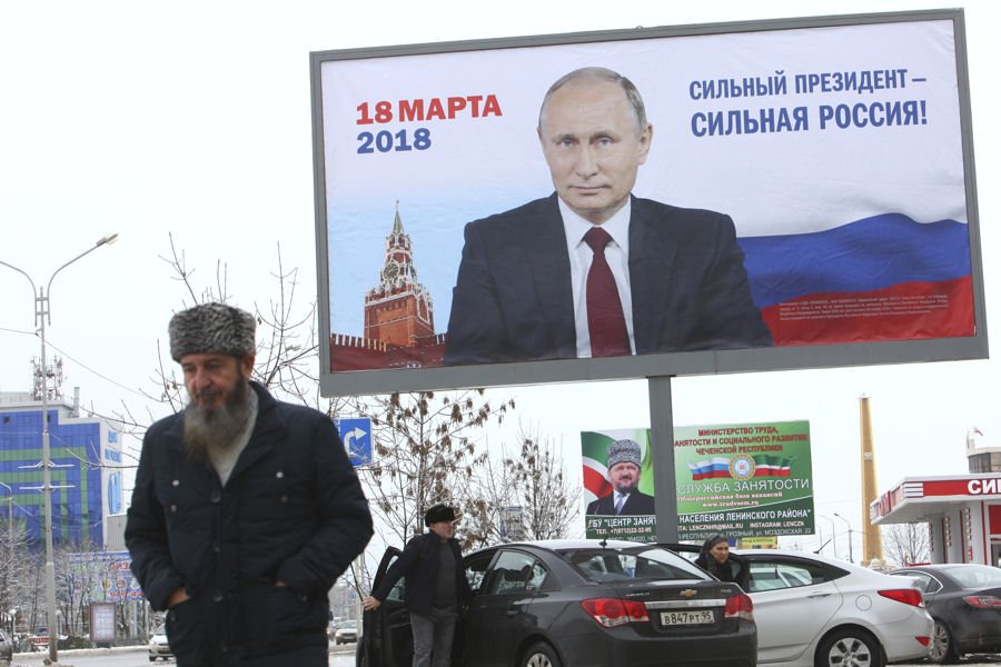 Мужчина проходит мимо предвыборного плаката с фотографией Путина и надписью: "Сильный президент - сильная Россия" в Грозном. 17.01.18 (© picture-alliance/AP)