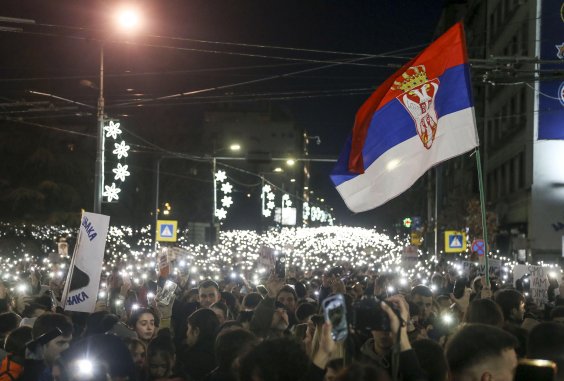 Belgrad ist (wieder) die Welt Das Bild zeigt einen Studentenprotest in Belgrad bei Nacht. Es sind mehrere Lichter und eine serbische Flagge zu sehen.