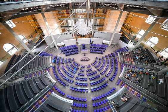 Teaserbild Themenseite Bundestagswahl 2025 Blick von oben auf die Sitzreihen des Deutschen Bundestags. Die Sitzreihen bestehen aus blauen Stühlen, die im Halbkreis um ein Rednerpult angeordnet sind. Im Hintergrund hängt ein metallener Adler an der Wand.