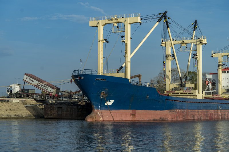 Ein Laster befüllt ein Frachtschiff mit einer Ladung Getreide.