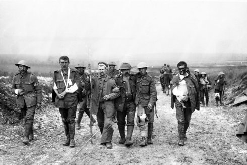 Ein deutscher Gefangener stützt britischen Verwundete auf dem Weg nach Bernafay während der Somme-Schlacht, 19. Juli 1916.