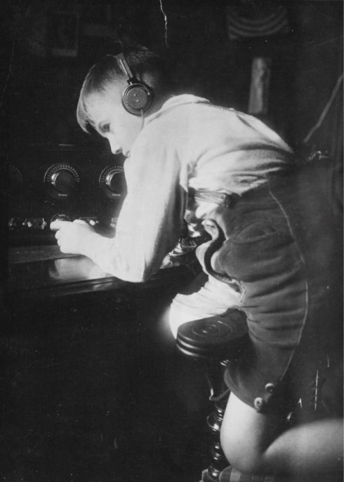 Etwa 12-jähriger Bub an einem Radioapparat. Um 1930. Photographie.