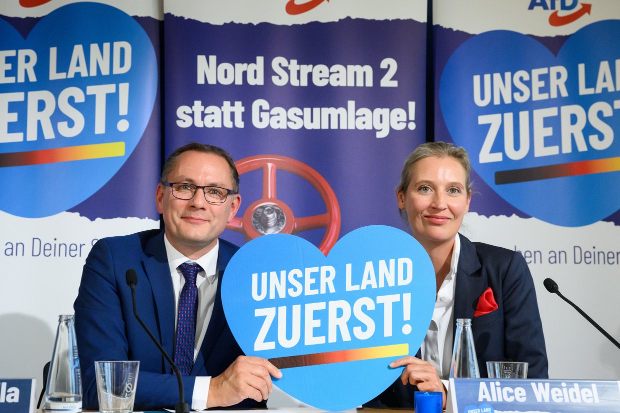 Tino Chrupalla und Alice Weidel präsentieren bei einer Pressekonferenz eine Kampagne der AfD. Dabei halten sie gemeinsam eine Herz mit der Aufschrift Unser Land zuerst!